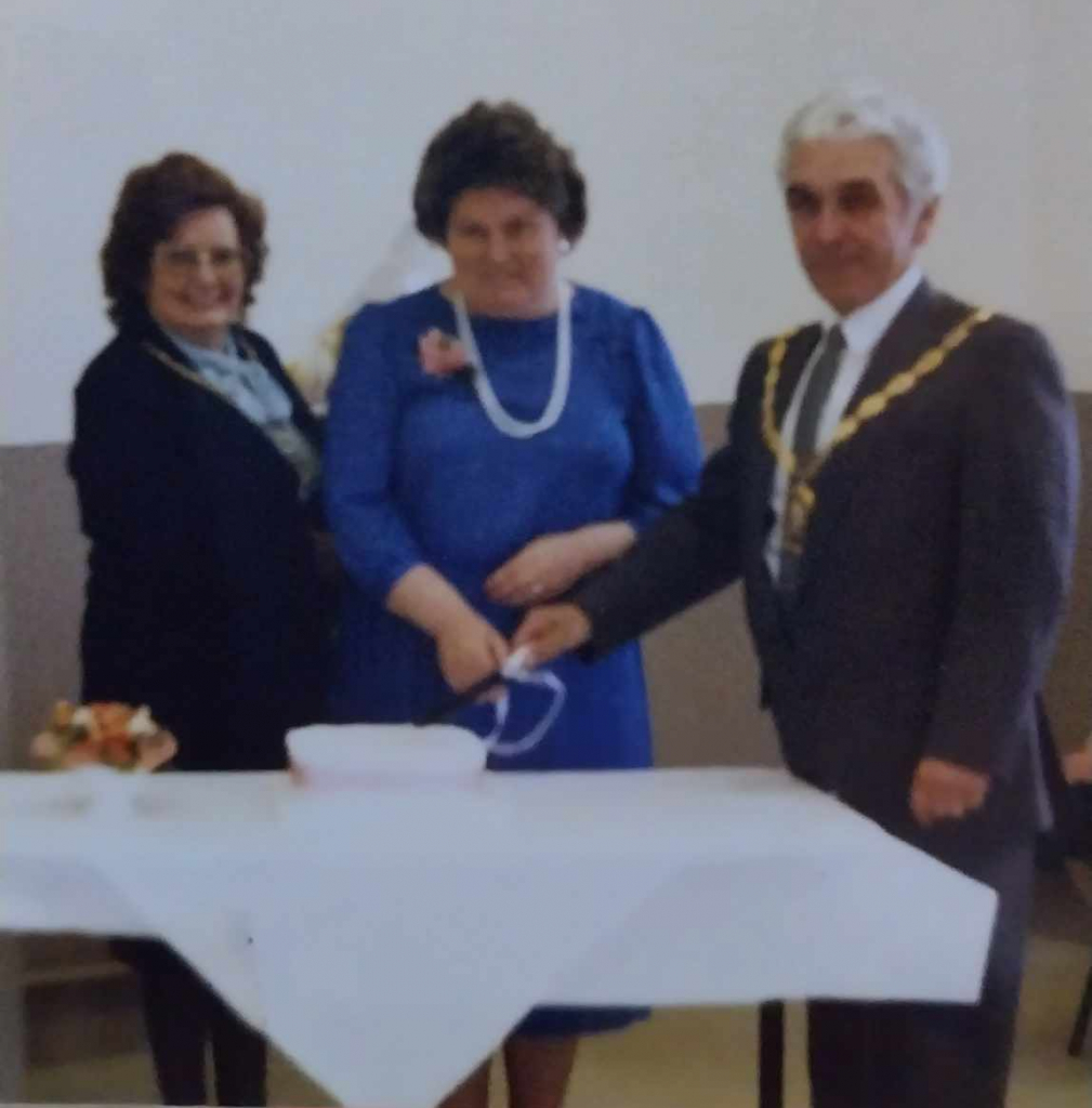 Three people cutting cake in the hall