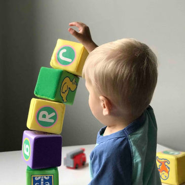 Toddler building a toy tower which is about to collapse